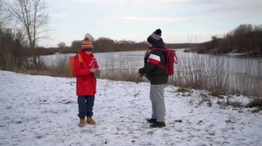 İki çocuk nehir kenarında karda oynuyor..