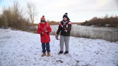 İki arkadaş, soğuk bir nehir kıyısında birbirlerine ısınırlar..