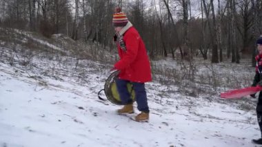 Çocuklar kışın karlı bir tepeden kayıyor..