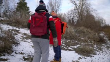 Çocuklar kışın karla birlikte nehir kenarını keşfediyorlar.