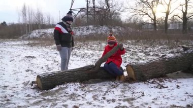 Çocuklar karda kütüklerle oynarken eğleniyor.