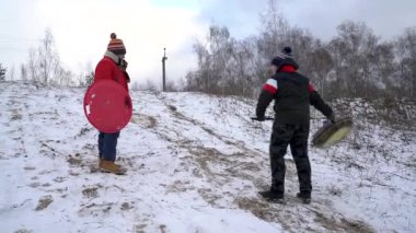 Karlı bir tepeden aşağıya iki kişi kayıyor..