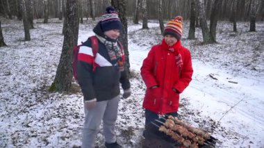 Çocuklar karlı ağaçlarda şiş pişiriyor..