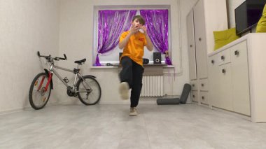 Yetenekli bir dansçı modern bir odada etkileyici hareketler sergiliyor. Bir bisiklet ve hoparlörlerin yer aldığı şık detaylarla süslenmiş. Boşluktaki enerji performansı artırır..