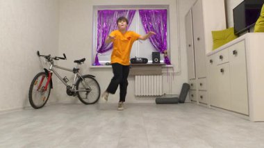 Bir dansçı, perdeler ve kişisel eşyalarla dekore edilmiş rahat bir mekanda enerjik bir rutin sergiler. Atmosfer müzik ve hareketlerle dolu..