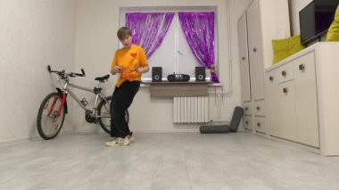 Genç bir çocuk dans figürlerini mor dekorla süslenmiş parlak ışıklı bir odada sergiliyor. Müzikten ve ritimden hoşlanan bir bisiklet duvara yaslanır..