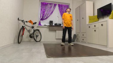 Genç bir dansçı mor perdelerle süslenmiş parlak bir odada hareket eder. Yakınlarda bir bisiklet ve ses sistemi var, enerjik bir atmosfer yaratıyorlar..