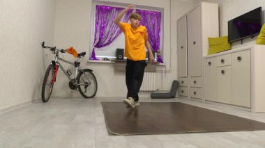 Genç bir dansçı mor perdelerle süslenmiş parlak bir odada hareket eder. Yakınlarda bir bisiklet ve ses sistemi var, enerjik bir atmosfer yaratıyorlar..