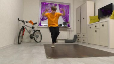 Genç bir dansçı mor perdelerle süslenmiş parlak bir odada hareket eder. Yakınlarda bir bisiklet ve ses sistemi var, enerjik bir atmosfer yaratıyorlar..