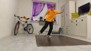 Genç bir dansçı mor perdelerle süslenmiş parlak bir odada hareket eder. Yakınlarda bir bisiklet ve ses sistemi var, enerjik bir atmosfer yaratıyorlar..