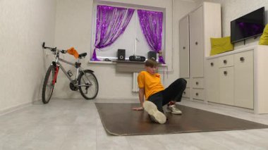 Genç bir dansçı mor perdelerle süslenmiş parlak bir odada hareket eder. Yakınlarda bir bisiklet ve ses sistemi var, enerjik bir atmosfer yaratıyorlar..