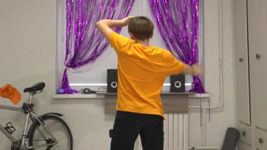 Genç bir dansçı mor perdelerle süslenmiş parlak bir odada hareket eder. Yakınlarda bir bisiklet ve ses sistemi var, enerjik bir atmosfer yaratıyorlar..