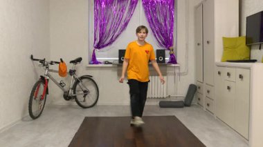 Genç bir dansçı mor perdelerle süslenmiş parlak bir odada hareket eder. Yakınlarda bir bisiklet ve ses sistemi var, enerjik bir atmosfer yaratıyorlar..