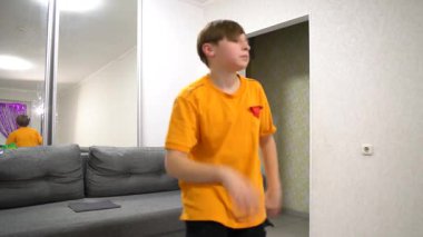 Turuncu elbiseli bir genç evde modern dans ediyor..