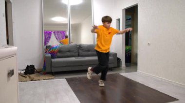 Genç bir dansçı, yumuşak ışıkla aydınlatılmış rahat bir oturma odasında etkileyici hareketler sergiliyor. Canlı dekor, akşam performansına neşe katıyor..