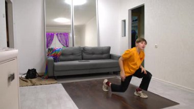 Genç bir dansçı, yumuşak ışıkla aydınlatılmış rahat bir oturma odasında etkileyici hareketler sergiliyor. Canlı dekor, akşam performansına neşe katıyor..