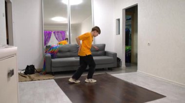 Bir çocuk renkli ışıklar ve rahat bir kanepeyle süslenmiş parlak bir oturma odasında enerjik bir dans sergiliyor. Atmosfer canlı ve neşe dolu, saf mutluluğun gösterişli anları..