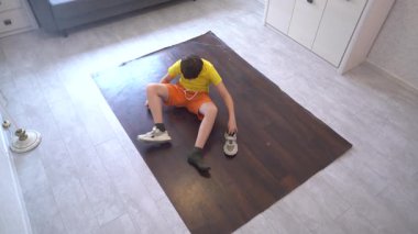 Genç bir dansçı modern bir oturma odasında break dans hareketi yapıyor. Renkli ışıklandırma ve dekor o antrenman yaparken enerjik atmosferi güçlendirir.