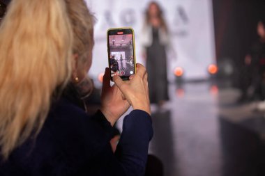 Şubat 01, 2024. Belarus, Gomel şehri. İnsanlar bir defilede podyumda mankenlerin fotoğraflarını çekiyor.