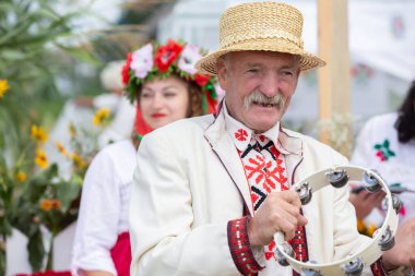 Belarus, Lyaskovichi köyü. 20 Ağustos 2022. Ulusal kültürlerin kutlaması. Beyaz Rusyalı bir adamın resmi tef ile ulusal giysiler içinde.