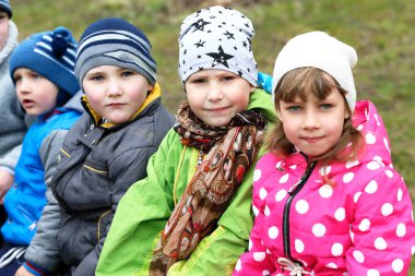 28 Nisan 2017. Beyaz Rusya. Gom. Park alanı. Bir grup çocuk şapka ve ceket giyiyor ve birlikte oturuyorlar. Manzara neşeli ve eğlenceli.
