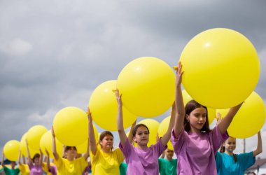 29 Temmuz 2023. Belarus, Lyaskovichi köyü. Etnik kültürlerin kutlaması. Kocaman sarı balonları olan bir grup çocuk..