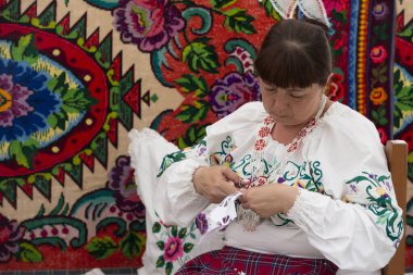 29 Temmuz 2023. Belarus, Lyaskovichi köyü. Ulusal kültürlerin kutlaması. Ulusal Slav elbiseli bir kadın nakış işliyor..