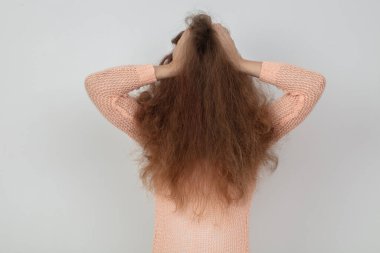 Sade bir arkaplanda stres ya da saç bakımı sorunları gösteren dağınık saçlı bir kadının arka planı