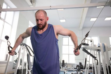 Erkek sporcu vücut geliştirici spor salonunda egzersiz yapıyor. Bir kablo makinesinde güç eğitimi.