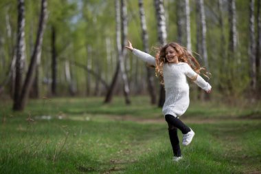 Küçük bir kız bahar ormanında koşuyor. Parkta yürüyen bir çocuk..