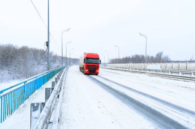 Ulyanovsk, Rusya - 13 Şubat 2022: Yarı karavan, yarı kamyon, traktör ünitesi ve yük taşımak için yarı römork. Kargo taşımacılığı sert kış koşullarında kaygan, buzlu ve karlı yollarda.