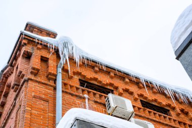 Konut binasının girişinde büyük buz saçakları var. Binanın girişine buz saçakları asmak, hayatı tehlikeye atar. Keskin buz sarkıtları eski bir apartmanın çatısında asılı..