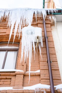 Konut binasının girişinde büyük buz saçakları var. Binanın girişine buz saçakları asmak, hayatı tehlikeye atar. Keskin buz sarkıtları eski bir apartmanın çatısında asılı..