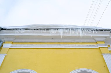 Konut binasının girişinde büyük buz saçakları var. Binanın girişine buz saçakları asmak, hayatı tehlikeye atar. Keskin buz sarkıtları eski bir apartmanın çatısında asılı..