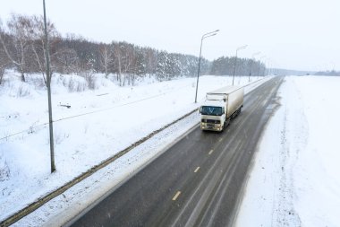 Yarı karavan kamyonu, yarı kamyon, traktör ünitesi ve yük taşımak için yarı karavan. Kargo taşımacılığı sert kış koşullarında kaygan, buzlu ve karlı yollarda.