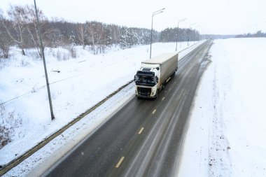 Yarı karavan kamyonu, yarı kamyon, traktör ünitesi ve yük taşımak için yarı karavan. Kargo taşımacılığı sert kış koşullarında kaygan, buzlu ve karlı yollarda.