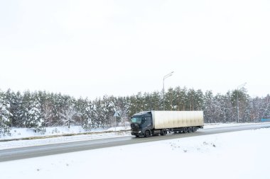 Yarı karavan kamyonu, yarı kamyon, traktör ünitesi ve yük taşımak için yarı karavan. Kargo taşımacılığı sert kış koşullarında kaygan, buzlu ve karlı yollarda.