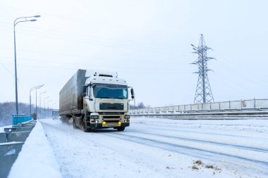 Ulyanovsk, Rusya - 13 Şubat 2022: Yarı karavan, yarı kamyon, traktör ünitesi ve yük taşımak için yarı römork. Kargo taşımacılığı sert kış koşullarında kaygan, buzlu ve karlı yollarda.