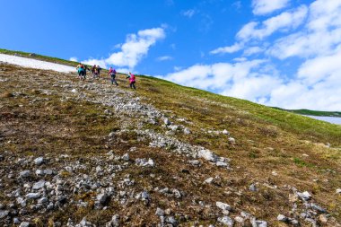 Bir grup turist ya da yürüyüşçü dağın zirvesinde yürür.