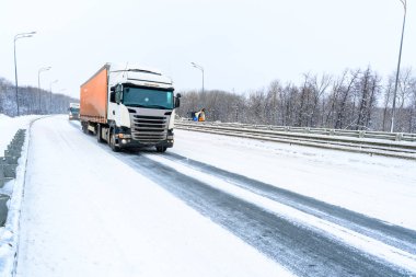 Ulyanovsk, Rusya - 13 Şubat 2022: Yarı karavan, yarı kamyon, traktör ünitesi ve yük taşımak için yarı römork. Kargo taşımacılığı sert kış koşullarında kaygan, buzlu ve karlı yollarda.