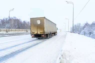 Ulyanovsk, Rusya - 13 Şubat 2022: Yarı karavan, yarı kamyon, traktör ünitesi ve yük taşımak için yarı römork. Kargo taşımacılığı sert kış koşullarında kaygan, buzlu ve karlı yollarda.