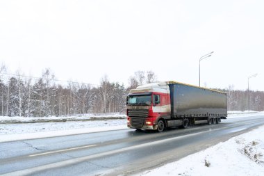 Yarı karavan kamyonu, yarı kamyon, traktör ünitesi ve yük taşımak için yarı karavan. Kargo taşımacılığı sert kış koşullarında kaygan, buzlu ve karlı yollarda.