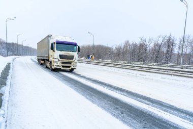 Ulyanovsk, Rusya - 13 Şubat 2022: Yarı karavan, yarı kamyon, traktör ünitesi ve yük taşımak için yarı römork. Kargo taşımacılığı sert kış koşullarında kaygan, buzlu ve karlı yollarda.