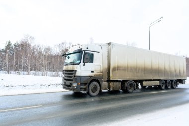 Yarı karavan kamyonu, yarı kamyon, traktör ünitesi ve yük taşımak için yarı karavan. Kargo taşımacılığı sert kış koşullarında kaygan, buzlu ve karlı yollarda.