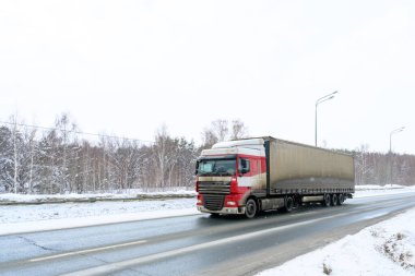 Yarı karavan kamyonu, yarı kamyon, traktör ünitesi ve yük taşımak için yarı karavan. Kargo taşımacılığı sert kış koşullarında kaygan, buzlu ve karlı yollarda.