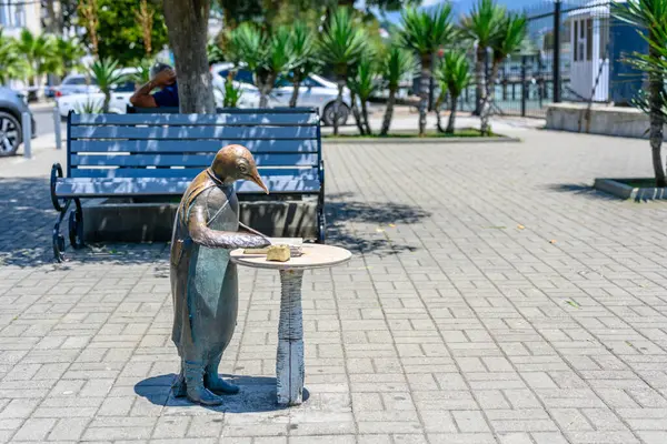stock image Sukhumi, Abkhazia, Georgia - 03 July, 2022: Sculpture of a penguin with an inkwell and a book on the waterfront.