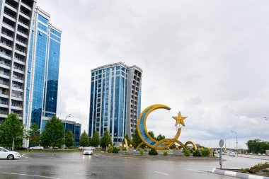 Argun, Çeçenistan, Rusya - 30 Haziran 2024: Argun şehrinin yüksek binaları ve yıldızlı hilal şeklinde stela manzarası.
