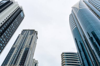 Grozny, Çeçenistan, Rusya - 30 Haziran 2024: Grozny City 'nin gökdelenleri. Mavi, bulutlu gökyüzüne karşı geniş, pencerelerle kaplı bir binanın açılı görüntüsü..