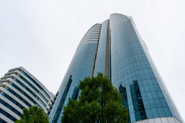 Grozny, Çeçenistan, Rusya - 30 Haziran 2024: Grozny City 'nin gökdelenleri. Mavi, bulutlu gökyüzüne karşı geniş, pencerelerle kaplı bir binanın açılı görüntüsü..