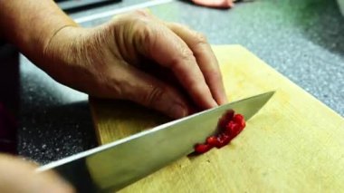 Mutfak tahtasında keskin bir bıçakla kırmızı dolma biberleri doğrayan bir aşçının yakın çekimi. Vejetaryen mutfağı. Lezzetli ve sağlıklı yemek kavramı. Seçici odak